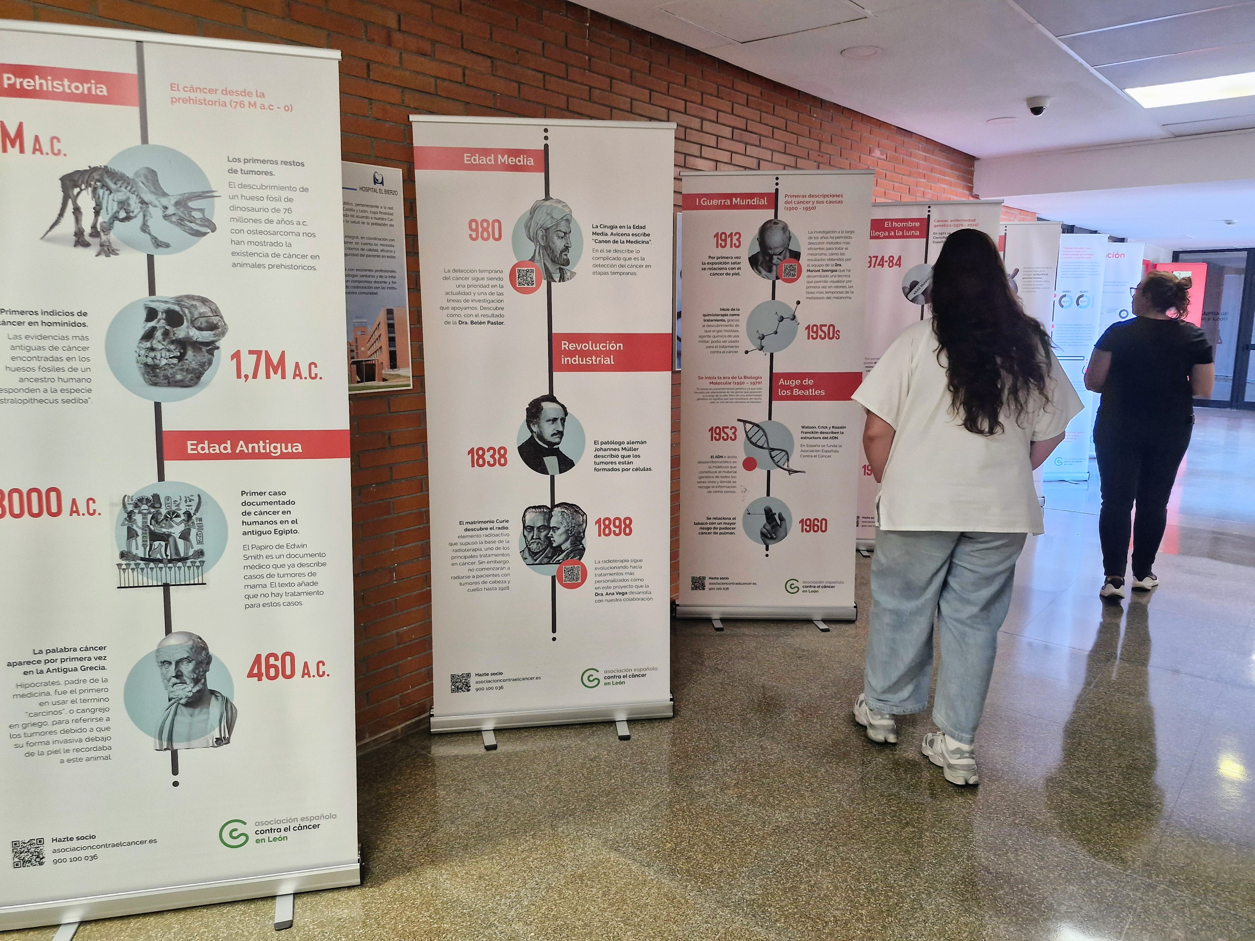 Dos personas observan la exposición de la Asociación Española Contra el Cáncer en el Hospital El Bierzo