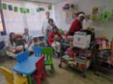 Papá Noel depositando los regalos donados en el Salón de Juegos de Pediatría junto a las sanitarias
