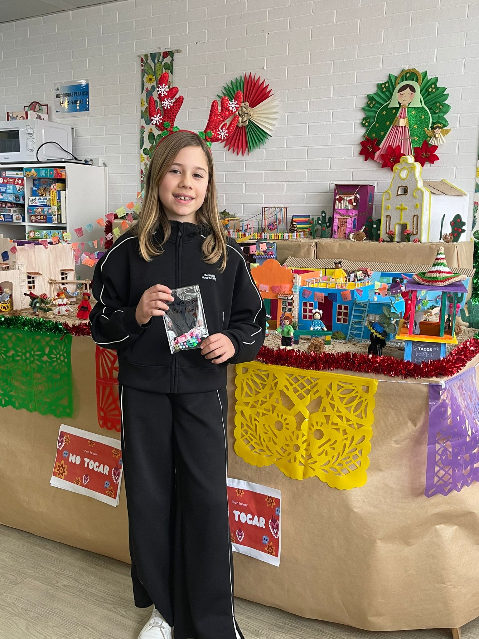 Adriana con una de sus pulseras hechas a mano frente al belén de la Sala de Juegos de Pediatría de la Gasbi